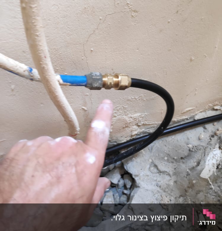 יד מצביעה על חיבור צינור מים עם מחבר מתכת